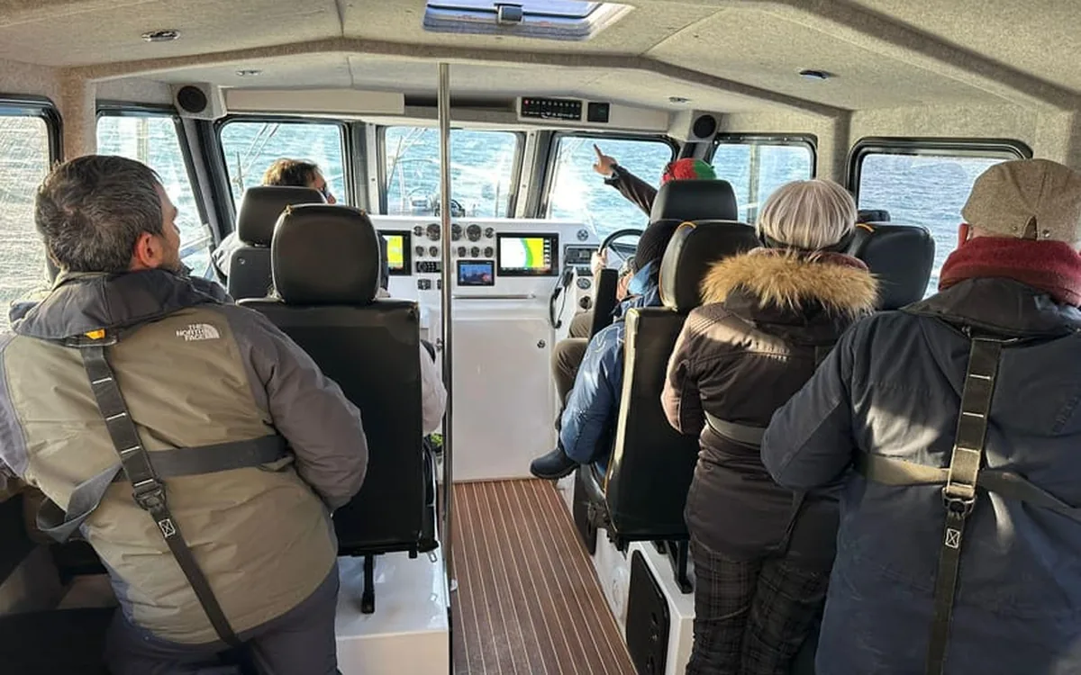 Guests sitting in the heated cabin of a whale watching boat